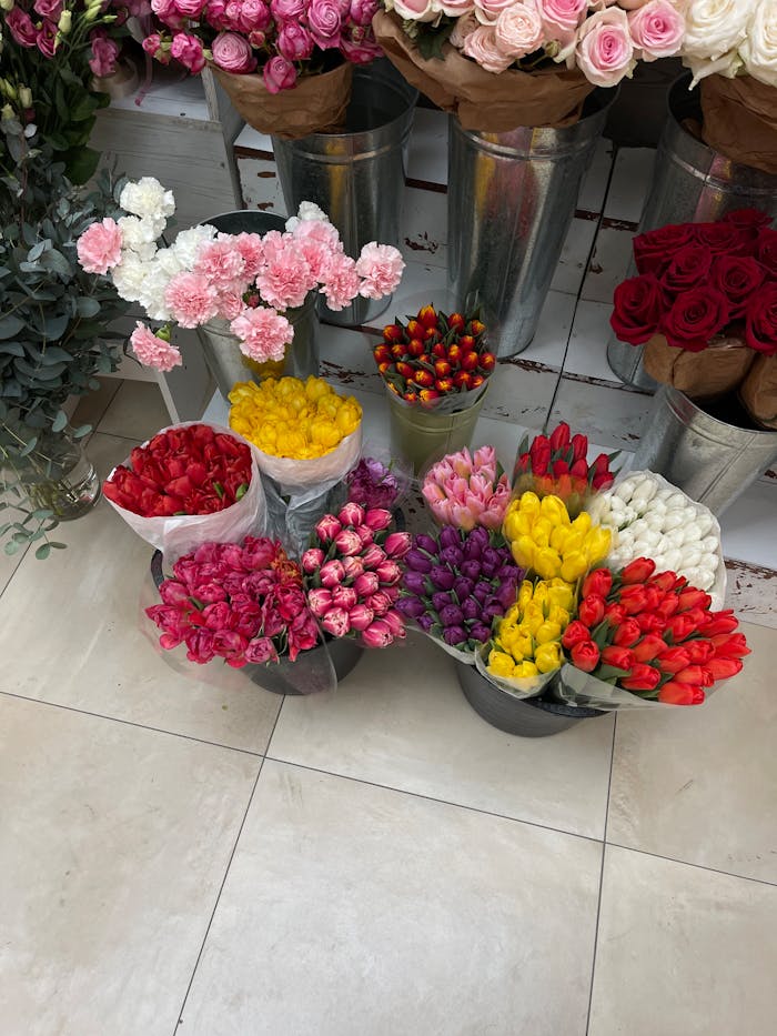 hero-img-02 Colorful floral arrangement of roses and tulips in metallic buckets, brightening an urban space.