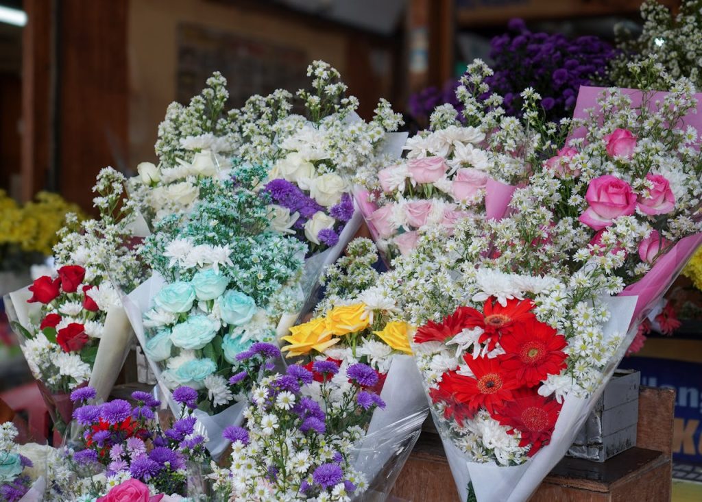 pexels-photo-36739287 Colorful flower bouquets displayed in a floral shop with roses and daisies.